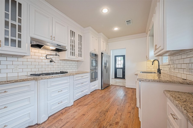 901 W 21st St, Houston, TX 77008 - kitchen with a sink, appliances with stainless steel finishes, under cabinet range hood, white cabinets, and light wood-style floors