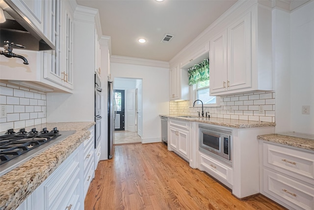 901 W 21st St, Houston, TX 77008 - kitchen with under cabinet range hood, a sink, white cabinets, appliances with stainless steel finishes, and recessed lighting
