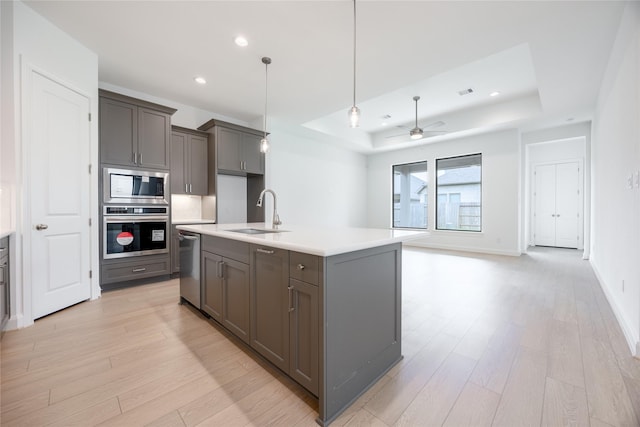 825 Coronado Terrace Ln, Katy, TX 77493 - kitchen with stainless steel appliances, a tray ceiling, light wood finished floors, light countertops, and gray cabinets