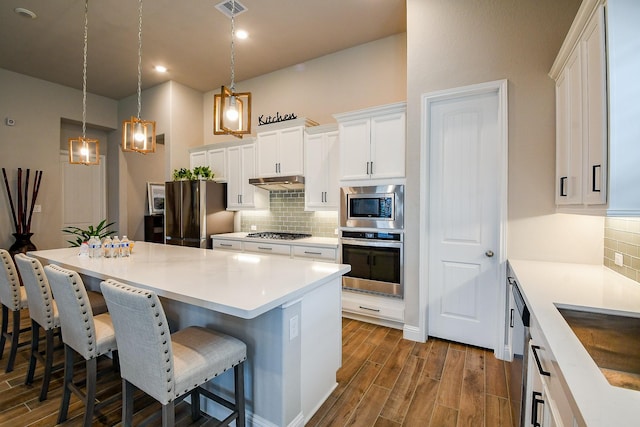 2234 Clements Shore Ln, La Porte, TX 77571 - kitchen featuring stainless steel appliances, dark wood-style flooring, tasteful backsplash, under cabinet range hood, and recessed lighting