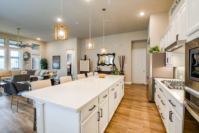 2234 Clements Shore Ln, La Porte, TX 77571 - kitchen with stainless steel appliances, a kitchen breakfast bar, a kitchen island, light wood finished floors, and light countertops