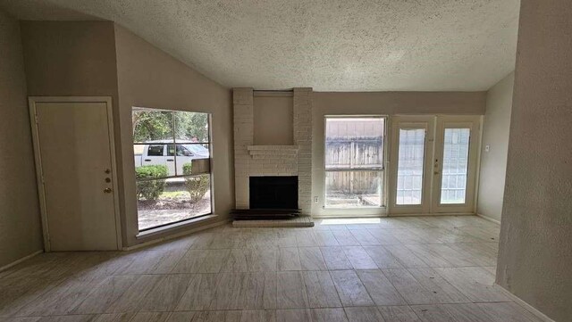 12107 Westwold Dr, Tomball, TX 77377 - unfurnished living room featuring a textured ceiling, a brick fireplace, lofted ceiling, and baseboards