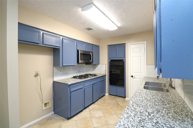 3911 Hermitage Hollow Ln, Houston, TX 77339 - kitchen with appliances with stainless steel finishes, a sink, blue cabinets, a warming drawer, and a textured ceiling