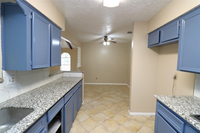 3911 Hermitage Hollow Ln, Houston, TX 77339 - kitchen with blue cabinetry, a textured ceiling, and baseboards