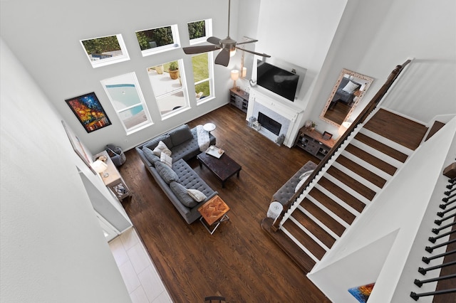 4807 Louisa Ct, Sugar Land, TX 77478 - living room featuring a towering ceiling, stairs, ceiling fan, a fireplace, and wood finished floors