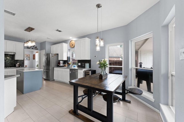 4807 Louisa Ct, Sugar Land, TX 77478 - kitchen featuring appliances with stainless steel finishes, decorative backsplash, a kitchen island, and white cabinetry