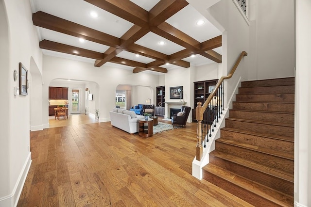 2319 Wyndam Heights Ln, Houston, TX 77077 - living room featuring arched walkways, stairs, beamed ceiling, coffered ceiling, and a fireplace