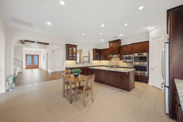 2319 Wyndam Heights Ln, Houston, TX 77077 - kitchen featuring arched walkways, stainless steel appliances, crown molding, backsplash, and under cabinet range hood