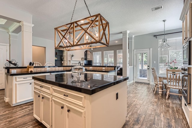 11519 Imperial Ln, Montgomery, TX 77316 - kitchen with decorative columns, a kitchen island, a textured ceiling, dark wood finished floors, and stainless steel oven