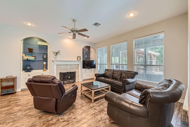 11519 Imperial Ln, Montgomery, TX 77316 - living room featuring a ceiling fan, wood finished floors, a tiled fireplace, and recessed lighting