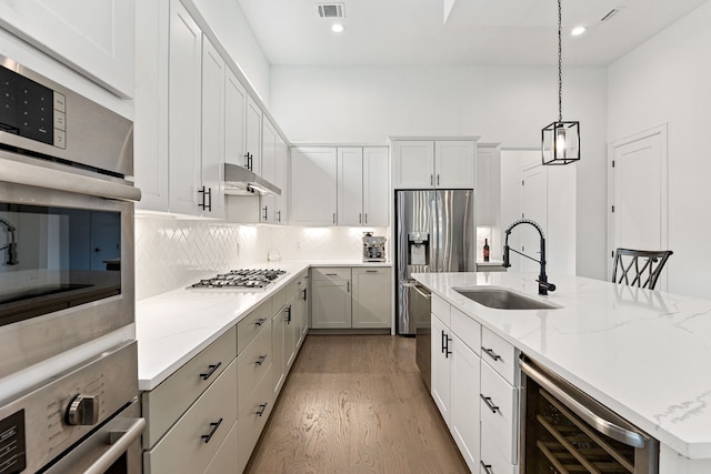 1433 Alexander St, Houston, TX 77008 - kitchen with wine cooler, a sink, appliances with stainless steel finishes, wood finished floors, and under cabinet range hood