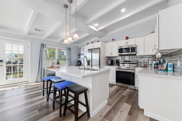 196 Barracuda St, Bayou Vista, TX 77563 - kitchen with appliances with stainless steel finishes, tasteful backsplash, a kitchen breakfast bar, beamed ceiling, and wood finished floors