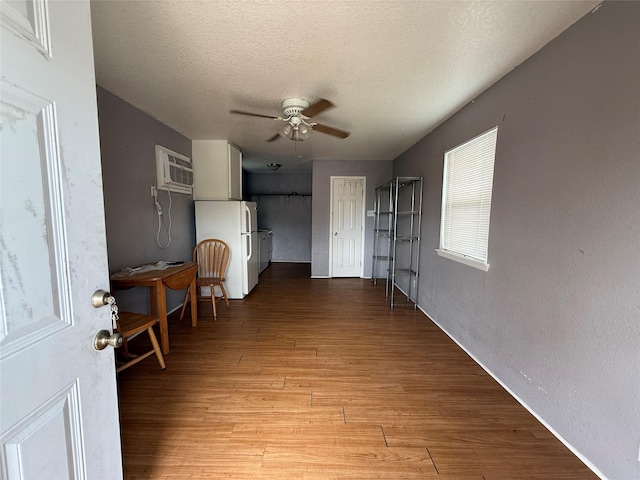 613 24th St, San Leon, TX 77539 - unfurnished living room featuring a wall unit AC, ceiling fan, light wood-style flooring, and a textured ceiling