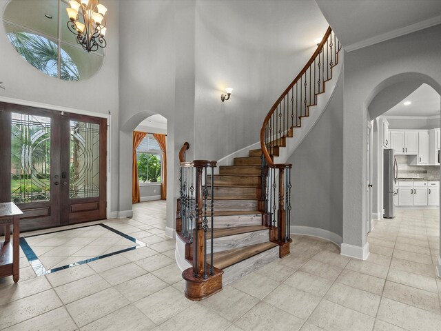 2905 Sea Channel Dr, Seabrook, TX 77586 - foyer entrance featuring arched walkways, baseboards, light tile patterned floors, a towering ceiling, and ornamental molding