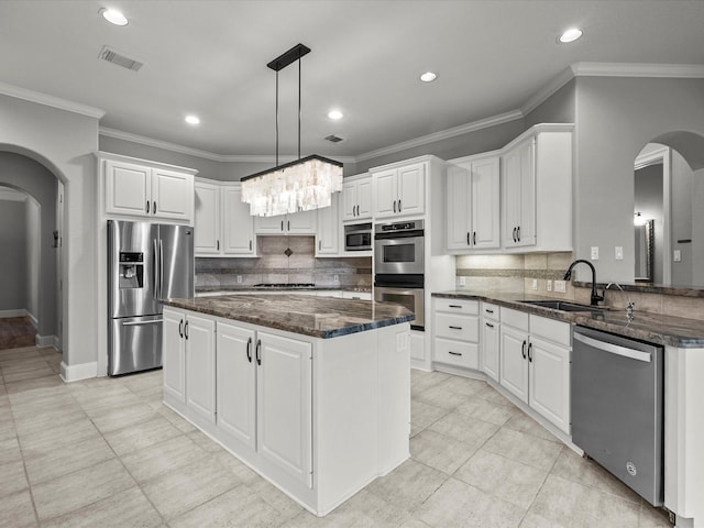 2905 Sea Channel Dr, Seabrook, TX 77586 - kitchen featuring arched walkways, stainless steel appliances, a sink, ornamental molding, and white cabinetry