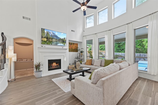 399 Black Walnut Dr, Conroe, TX 77304 - living area featuring a high ceiling, ceiling fan, a glass covered fireplace, and light wood-style floors