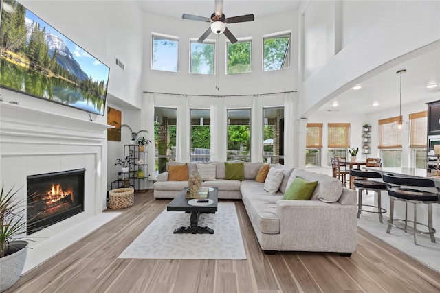 399 Black Walnut Dr, Conroe, TX 77304 - living area with a ceiling fan, wood finished floors, a tiled fireplace, a towering ceiling, and arched walkways