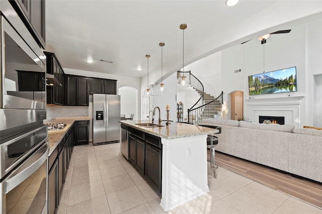 399 Black Walnut Dr, Conroe, TX 77304 - kitchen featuring appliances with stainless steel finishes, a sink, arched walkways, open floor plan, and light stone countertops