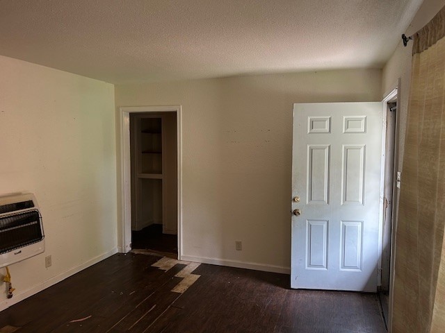 6619 Carver Ave, Hitchcock, TX 77563 - unfurnished room featuring heating unit, dark wood-style flooring, a textured ceiling, and baseboards