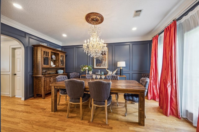 19 Remington Park, Katy, TX 77493 - dining area featuring a decorative wall, crown molding, a chandelier, light wood-type flooring, and arched walkways