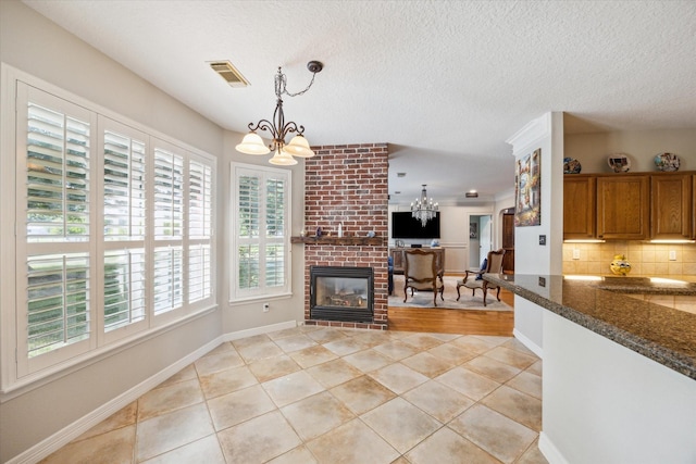 19 Remington Park, Katy, TX 77493 - kitchen featuring a chandelier, brown cabinets, light tile patterned floors, tasteful backsplash, and hanging light fixtures
