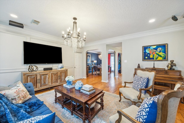 19 Remington Park, Katy, TX 77493 - living room featuring arched walkways, ornamental molding, a chandelier, light wood-style flooring, and a textured ceiling