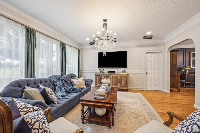 19 Remington Park, Katy, TX 77493 - living room with arched walkways, a chandelier, light wood-style flooring, ornamental molding, and a textured ceiling