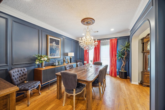 19 Remington Park, Katy, TX 77493 - dining space featuring ornamental molding, a chandelier, a decorative wall, a textured ceiling, and light wood finished floors