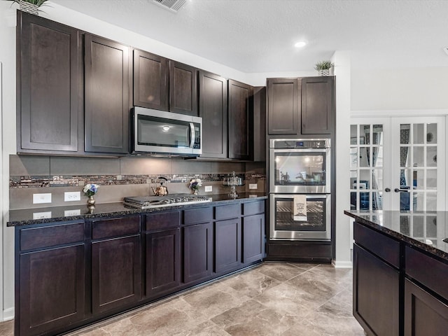 14306 Cedar Pine Ct, Houston, TX 77068 - kitchen with stainless steel appliances, dark stone countertops, dark brown cabinetry, and french doors