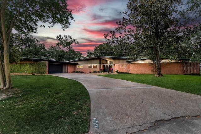 1240 Oakcrest Cir, Beaumont, TX 77706 - mid-century inspired home featuring a lawn, driveway, brick siding, and board and batten siding