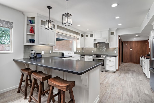 1240 Oakcrest Cir, Beaumont, TX 77706 - kitchen with stainless steel range with gas stovetop, a peninsula, decorative backsplash, dark countertops, and white cabinets