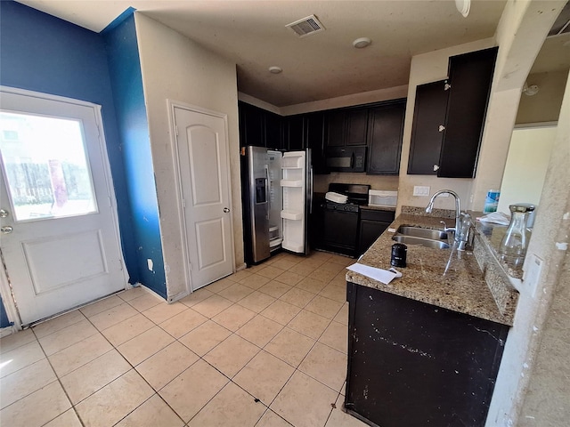 2419 Fort Baldy Trl, Humble, TX 77396 - kitchen with black appliances, a sink, light tile patterned floors, dark cabinets, and light stone countertops