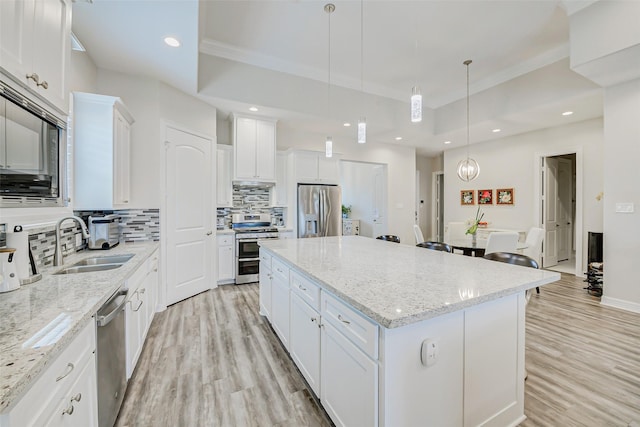 321 Twin Timbers Ln, Kemah, TX 77565 - kitchen with stainless steel appliances, a sink, a kitchen island, decorative backsplash, and light wood finished floors