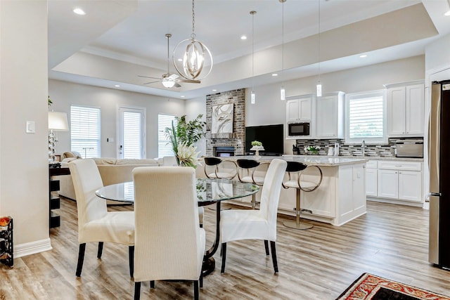 321 Twin Timbers Ln, Kemah, TX 77565 - dining room featuring a raised ceiling, light wood-style flooring, recessed lighting, ceiling fan, and a chandelier