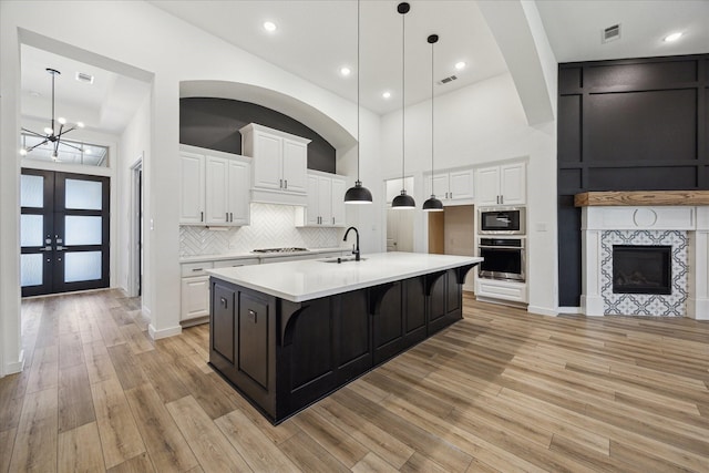 23910 Birchwood Lake Ln, Katy, TX 77493 - kitchen featuring appliances with stainless steel finishes, a sink, light countertops, light wood finished floors, and white cabinets
