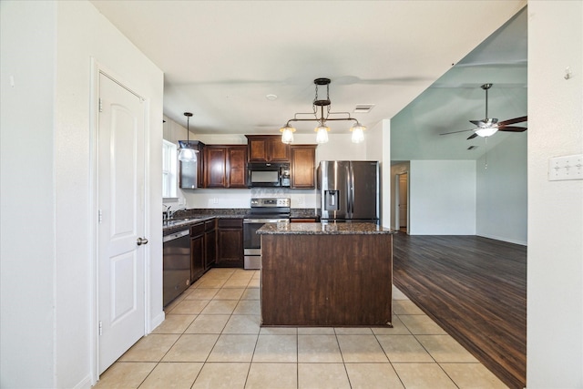 5002 Manor Stone Ln, Rosenberg, TX 77469 - kitchen featuring stainless steel appliances, a ceiling fan, a center island, light tile patterned flooring, and dark stone countertops