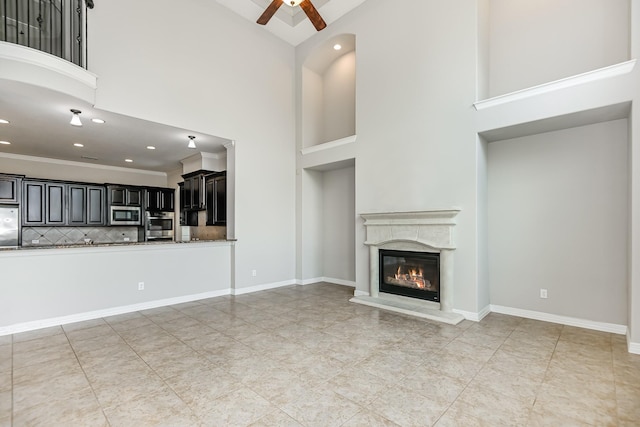 27415 Ashford Sky Ln, Katy, TX 77494 - unfurnished living room featuring a ceiling fan, a towering ceiling, a glass covered fireplace, recessed lighting, and light tile patterned floors
