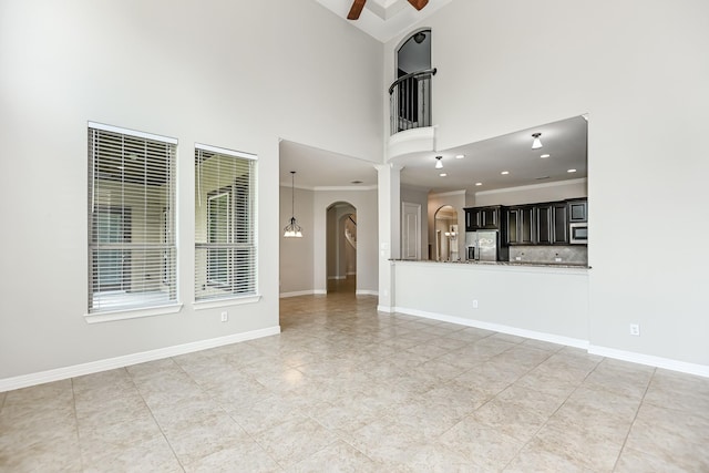 27415 Ashford Sky Ln, Katy, TX 77494 - unfurnished living room featuring a ceiling fan, a towering ceiling, arched walkways, light tile patterned floors, and ornamental molding
