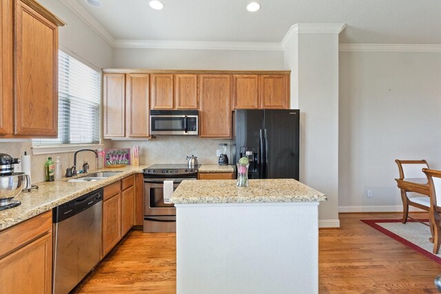 620 Cathedral Sq, Beaumont, TX 77701 - kitchen featuring stainless steel appliances, a sink, a kitchen island, light wood-style floors, and tasteful backsplash