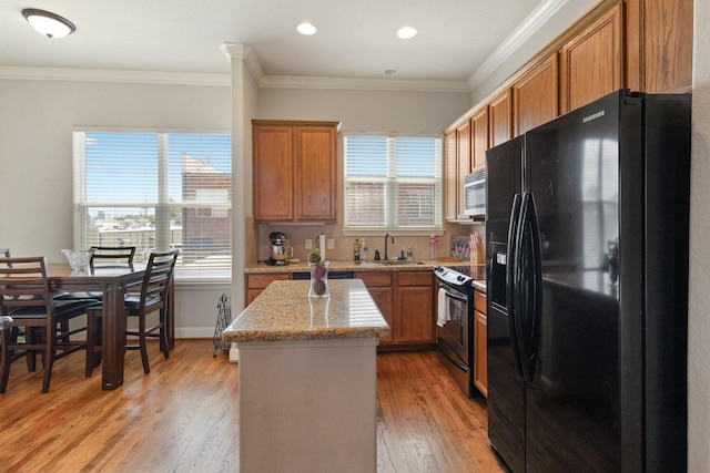 620 Cathedral Sq, Beaumont, TX 77701 - kitchen with appliances with stainless steel finishes, a kitchen island, light wood-style flooring, brown cabinets, and ornamental molding