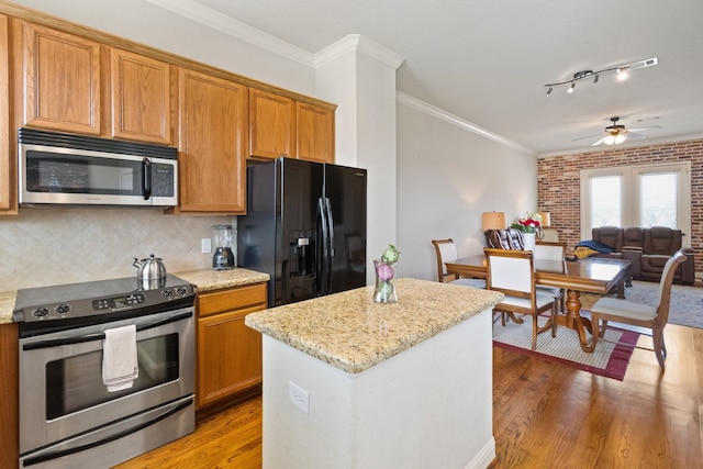 620 Cathedral Sq, Beaumont, TX 77701 - kitchen featuring appliances with stainless steel finishes, light wood-type flooring, ceiling fan, backsplash, and a kitchen island