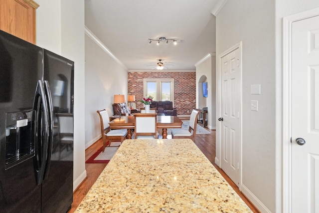 620 Cathedral Sq, Beaumont, TX 77701 - kitchen with black refrigerator with ice dispenser, dark wood-style flooring, crown molding, brick wall, and a ceiling fan