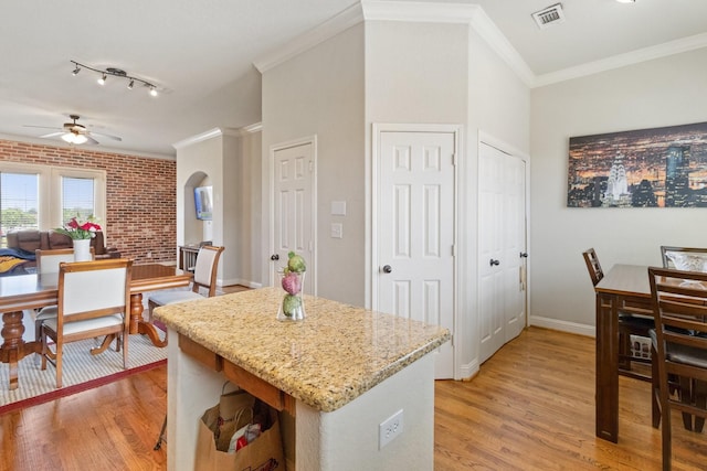 620 Cathedral Sq, Beaumont, TX 77701 - kitchen with light wood finished floors, a ceiling fan, light stone counters, arched walkways, and crown molding
