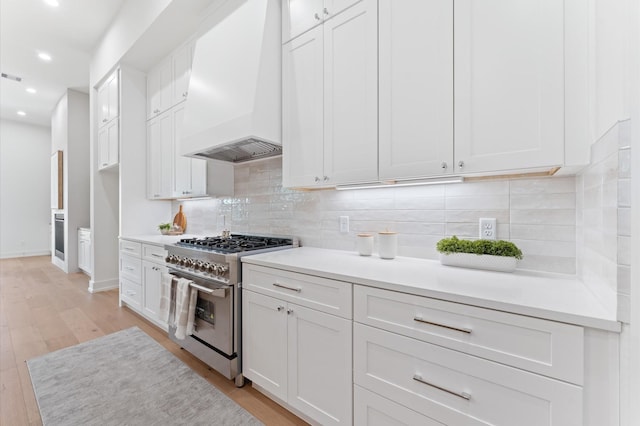 322 Aurora St, Houston, TX 77008 - kitchen with stainless steel stove, custom range hood, recessed lighting, white cabinets, and light wood-style floors
