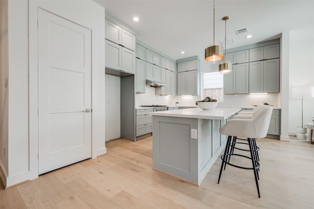 2015 Hopkins St, Houston, TX 77006 - kitchen with light wood-type flooring, gray cabinets, decorative backsplash, and recessed lighting