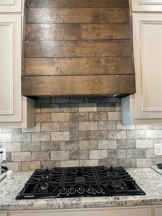 3295 Fm 524, Sweeny, TX 77480 - kitchen view of stovetop, backsplash, extractor fan, white cabinetry, and light stone countertops