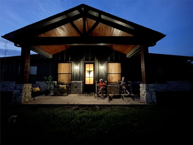3295 Fm 524, Sweeny, TX 77480 - back of house at twilight with stone siding, a patio area, and board and batten siding