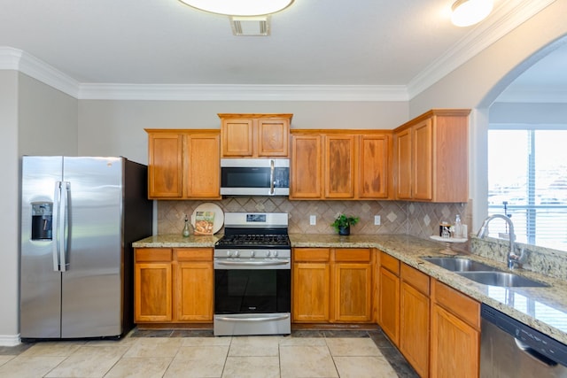 1802 Dominic Ln, Houston, TX 77049 - kitchen featuring stainless steel appliances, a sink, ornamental molding, arched walkways, and brown cabinets
