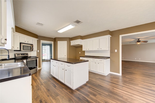1322 Village Garden Dr, Missouri City, TX 77459 - kitchen with appliances with stainless steel finishes, dark countertops, dark wood finished floors, white cabinets, and decorative backsplash
