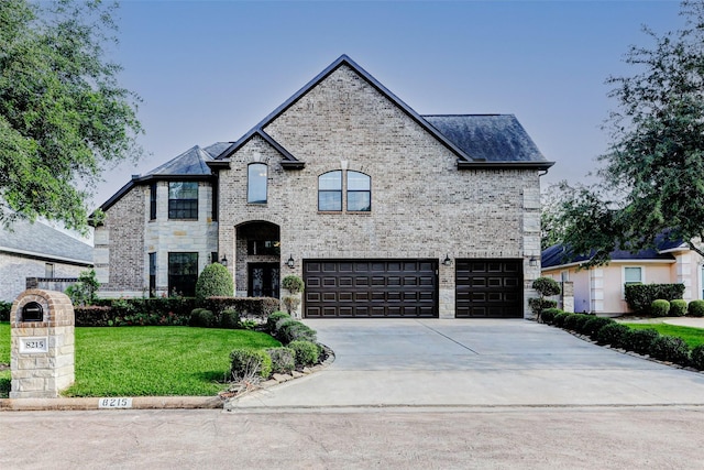 8215 Frontenac Dr, Houston, TX 77071 - french country home featuring a garage, driveway, a front yard, brick siding, and stone siding